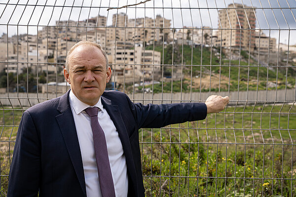Ed Davey stands in front of security fencing in East Jerusalem