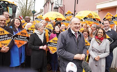 Ed Davey with laughing crowd holding Liberal Democrat diamond signs