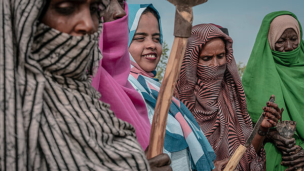 Four women in Sudan, holding agricultural tools