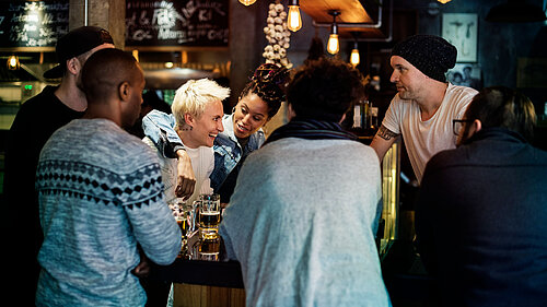 6 people smiling and drinking at a bar