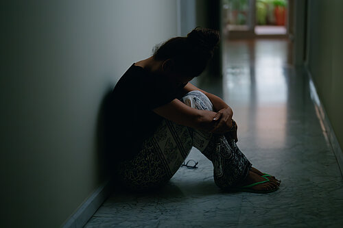 A woman sat in an empty corridor with her head in her knees