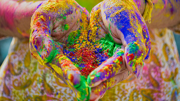 Hands holding Holi festival powder dyes in multiple colours