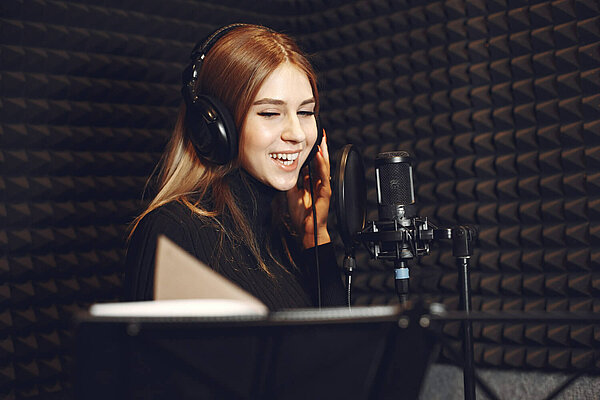 A woman and a microphone in a recording studio