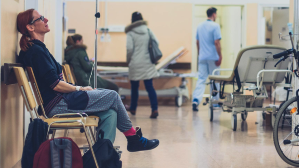 Woman sat on chair waiting in a hospital corridor