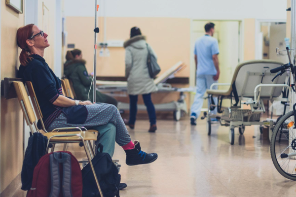 Woman sat on chair waiting in a hospital corridor