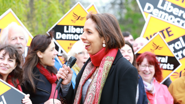 Munira Wilson in front of a crowd holding diamond posters