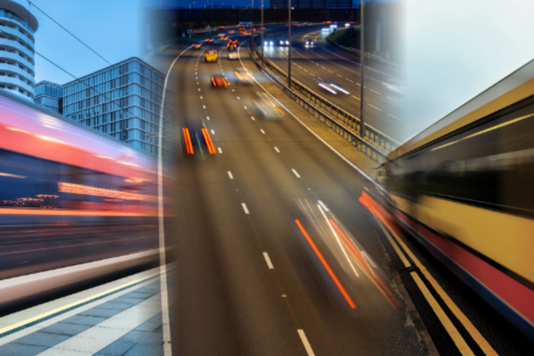 A train, cars and a bus, blurred by their motion