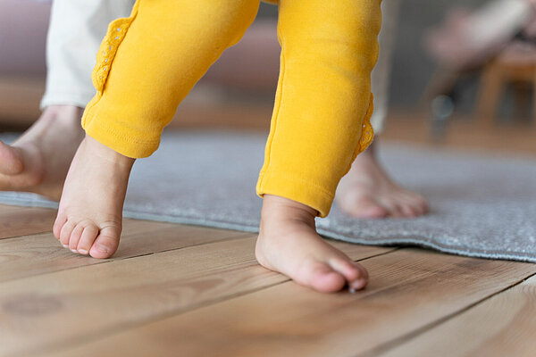 Photo baby learning how to walk and being helped by his mother