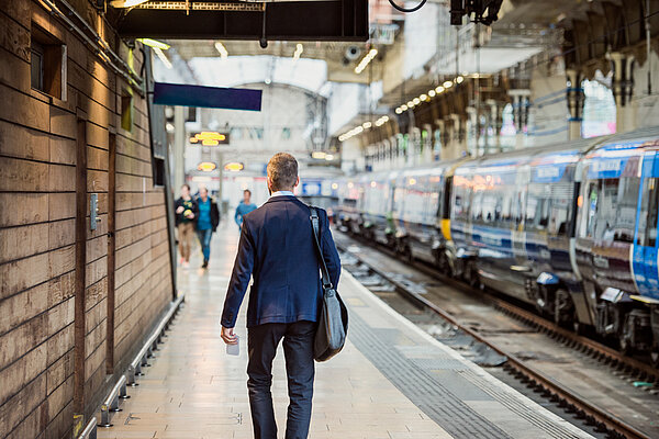 Person in suit walking away from camera at a train station