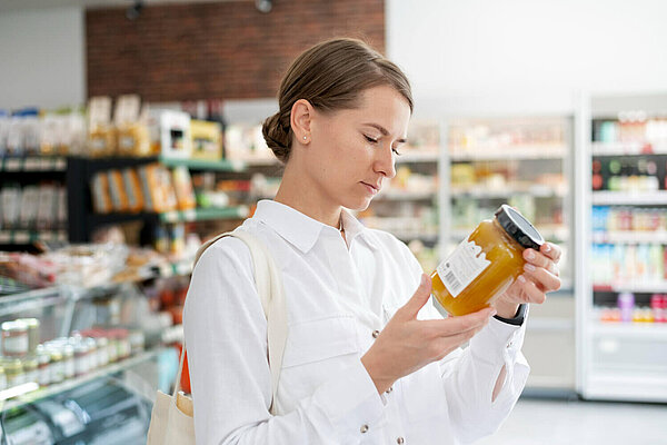 A woman looks at a label on a jar of food