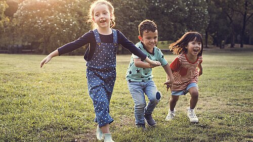 Three children running in a garden