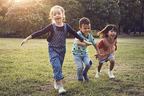 Three children running in a garden
