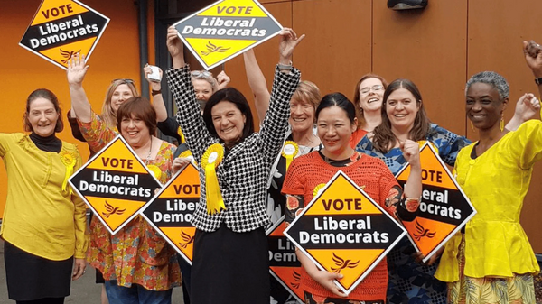 A group of Liberal Democrats holding signs and celebrating winning