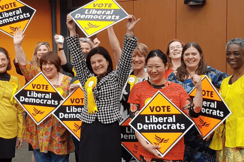 A group of Liberal Democrats holding signs and celebrating winning