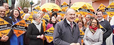 Ed Davey with laughing crowd holding Liberal Democrat diamond signs