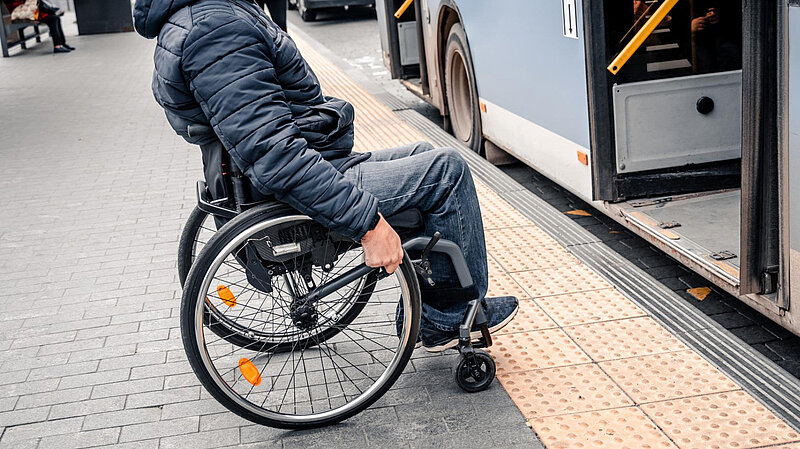 A wheelchair user approaches a bus door