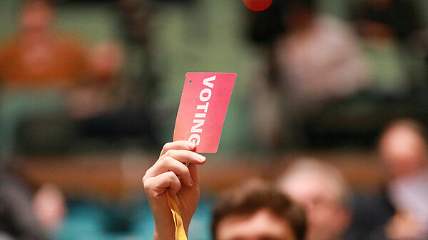 Person at Liberal Democrat conference holding their pass in the air to vote.