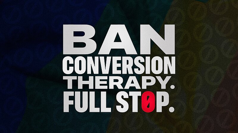 Banner with white text overlaid on a dark faded LGBT flag reading Ban Conversion Therapy Full Stop