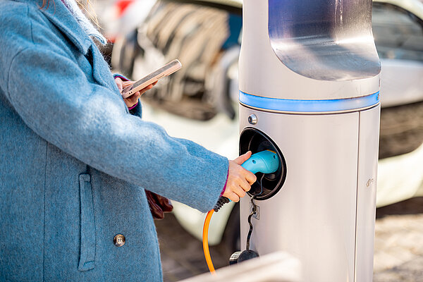 person pays on phone as they plug EV into charger