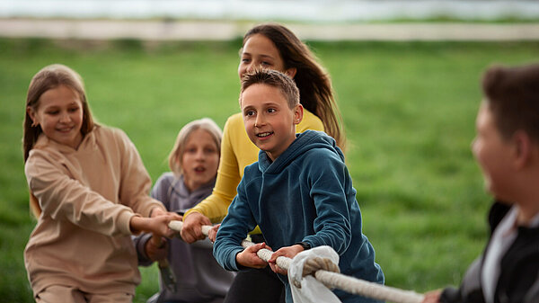 Photo of kids playing tug-of-war in the park