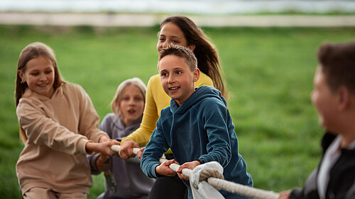 Photo of kids playing tug-of-war in the park