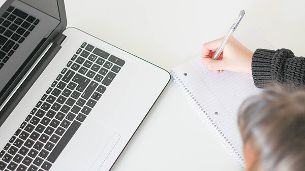 Making notes while looking at a laptop