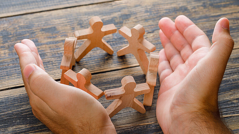Caring Hands surrounding wooden figures
