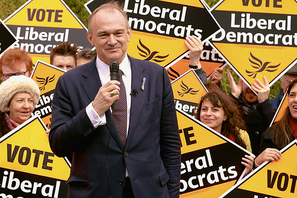 Ed Davey in front of a crowd of people holding diamond-shaped Liberal Democrat posters