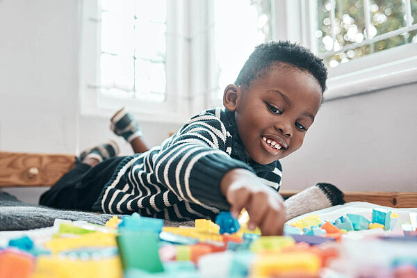 Child playing Child lying on floor playing with toys