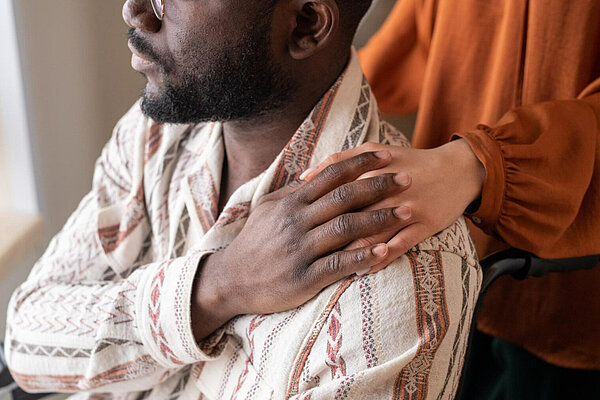 Carers Two people touching hands, one person is seated