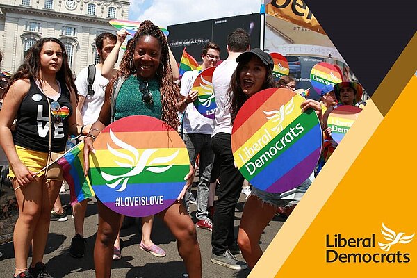 A group with Lib Dem lgbt pride signs on a Lib Dem membership card