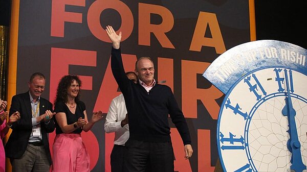 Ed Davey waves from conference stage