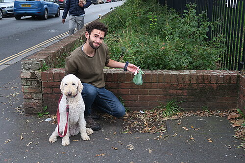 Will Aczel with dog, Ayla, holds up some rubbish by a former bin site on Old Tiverton Rd, Exeter.