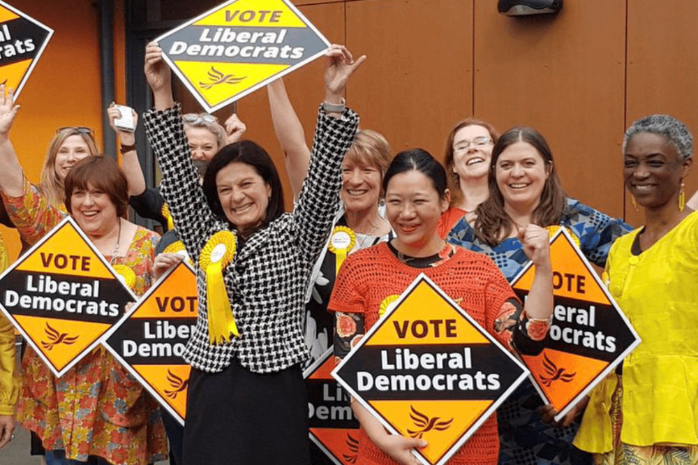 A group of Liberal Democrats holding signs and celebrating winning